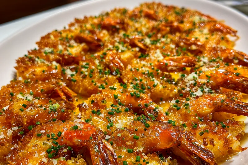 Chef frying Crispy Coconut Shrimp Delight in a skillet, showcasing the golden-brown crust.