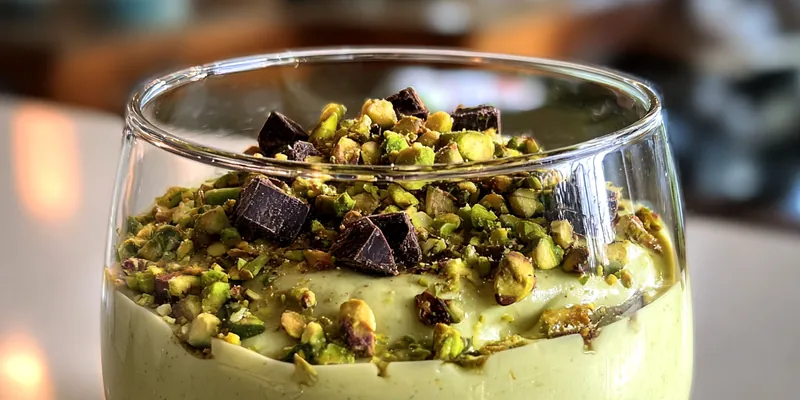 A beautifully plated bowl of Decadent Pistachio Mousse topped with crushed pistachios and a sprig of mint.